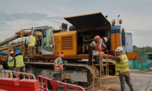 Construction project management team at worksite reviewing heavy equipment during federal shutdown delays
