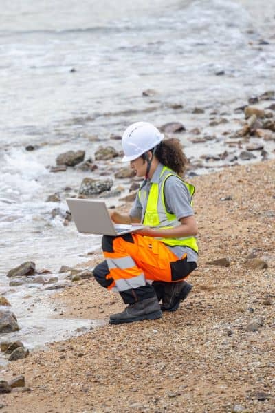Civil engineer inspecting site drainage near water as part of site design evaluation


