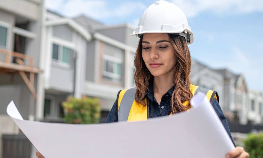Female civil engineer reviewing a site design plan outdoors before construction
