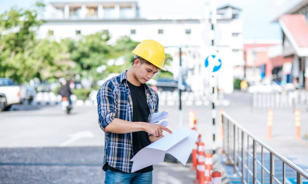 Civil engineer reviewing plans on an active roadway site as part of stormwater design planning for road and site projects