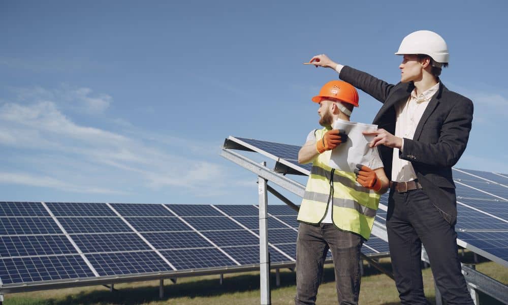 Geotechnical engineering team reviewing plans in front of solar panels during a landfill solar project
