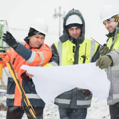 Engineers reviewing bridge plans during winter conditions, illustrating how structural engineering decisions guide safety actions
