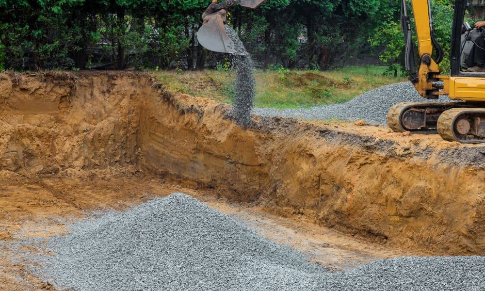 Soil engineer reviewing granular backfill placement at an excavation site before compaction