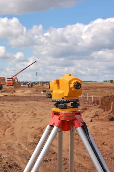Surveying equipment set up on a construction site with workers and machinery, illustrating accurate land measurement for subdivision planning
