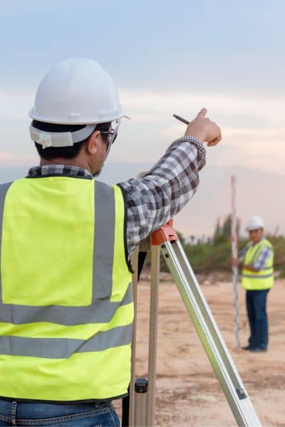 A surveyor marking property boundaries on a site before a commercial project begins