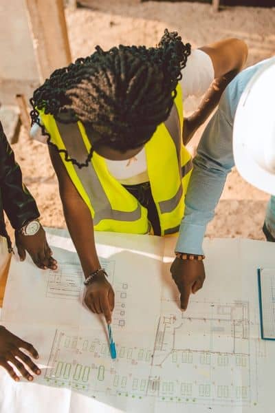 Engineers reviewing site plans together on a construction site while checking project details for an engineering firm